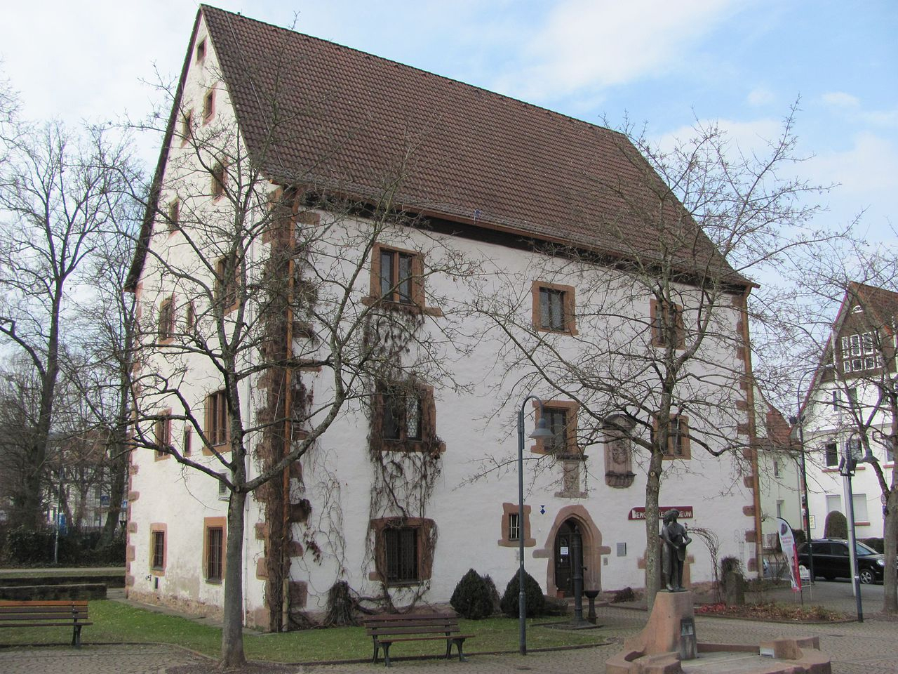 Ein dreistöckiges, weiß verputztes Gebäude aus dem 15. Jahrhundert, mit Satteldach